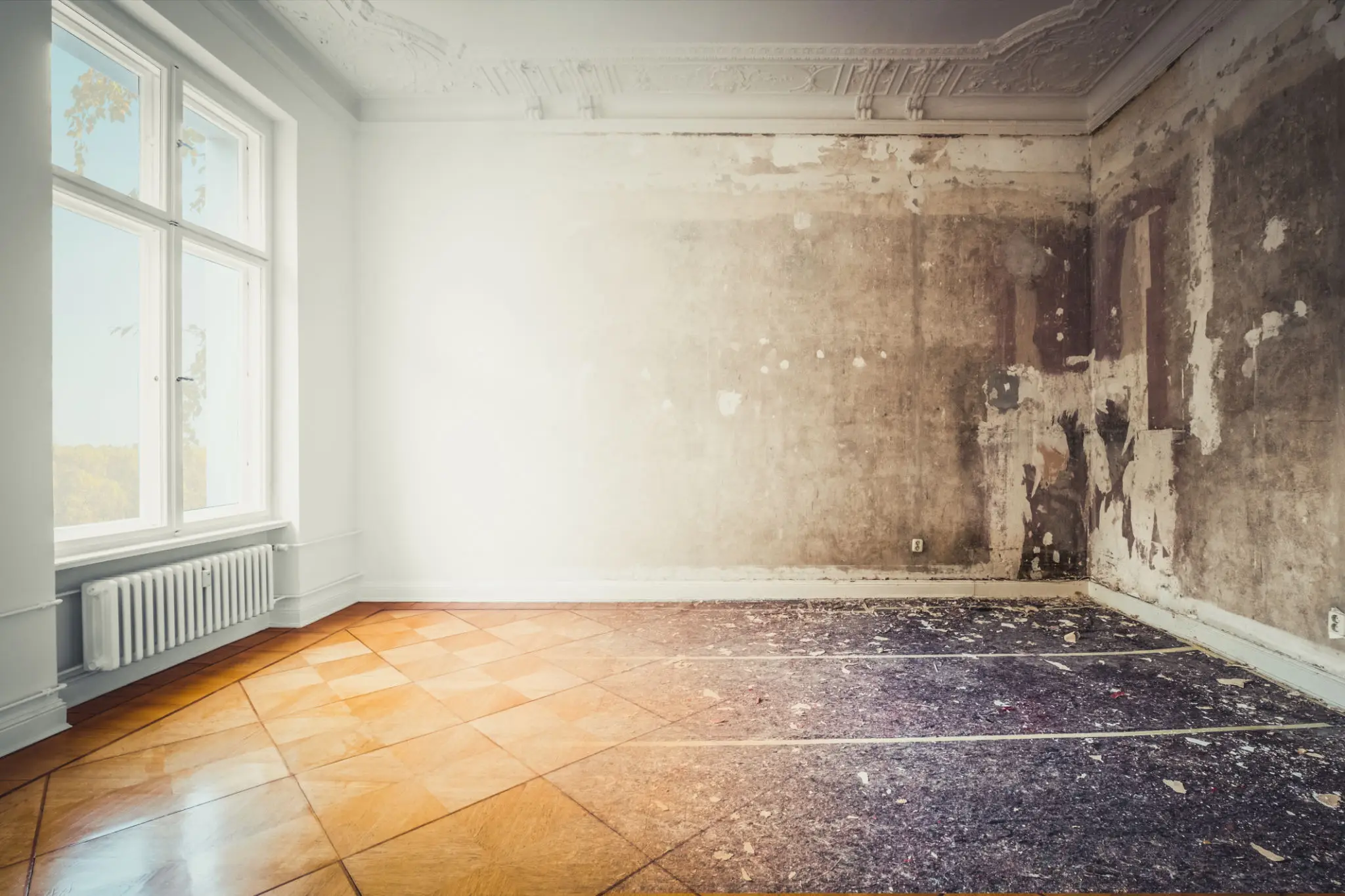 A room showing a contrast between a clean white wall and a worn, damaged wall.