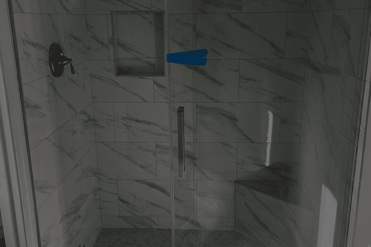 Modern bathroom shower area with glass doors and marble tiles.