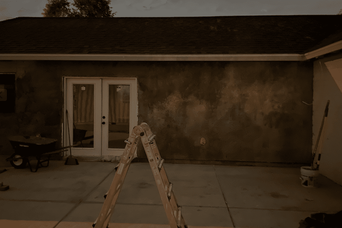 Wooden stepladder in front of a house with double doors at dusk.