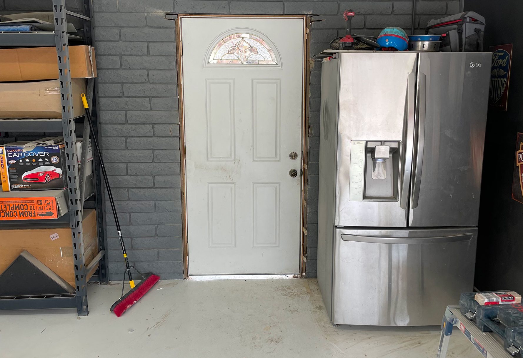 White door next to a stainless steel refrigerator in a garage setting.